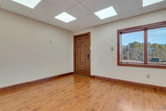 unfurnished room with a drop ceiling and light wood-type flooring