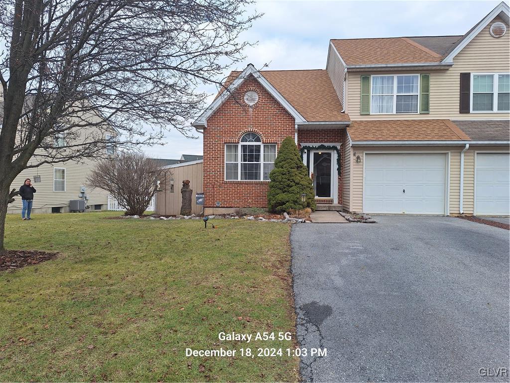 front of property featuring a front yard, a garage, and central air condition unit