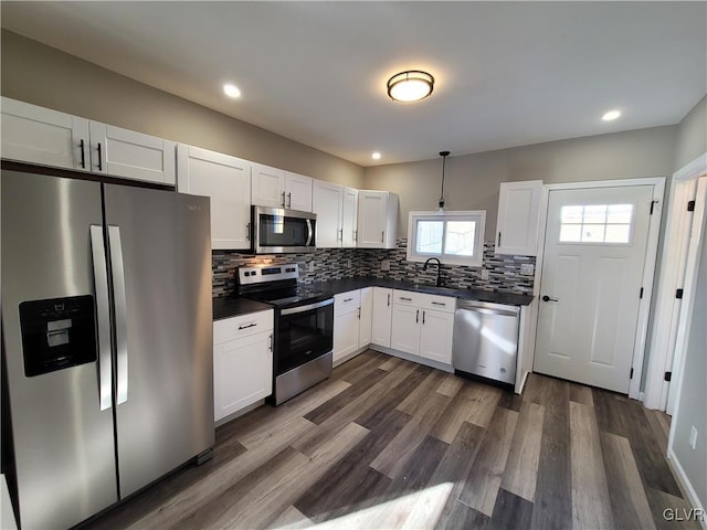 kitchen featuring appliances with stainless steel finishes, dark wood-type flooring, sink, pendant lighting, and white cabinetry