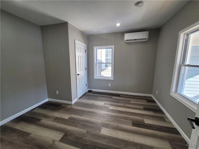 unfurnished room with a wall mounted air conditioner, dark hardwood / wood-style flooring, and plenty of natural light