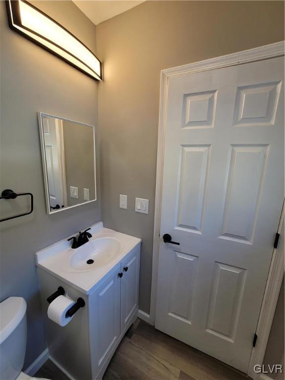 bathroom featuring toilet, vanity, and hardwood / wood-style flooring