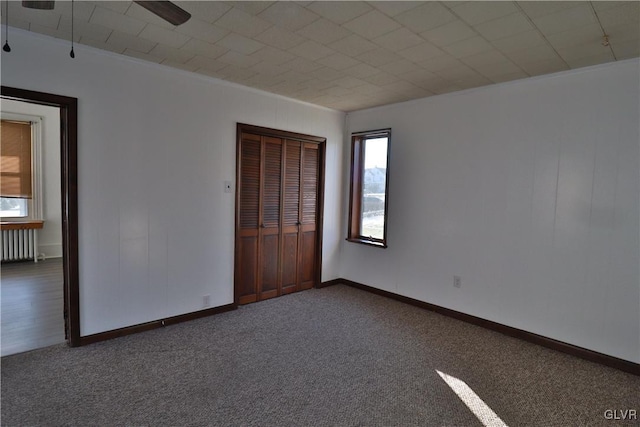 carpeted empty room featuring radiator heating unit and ceiling fan