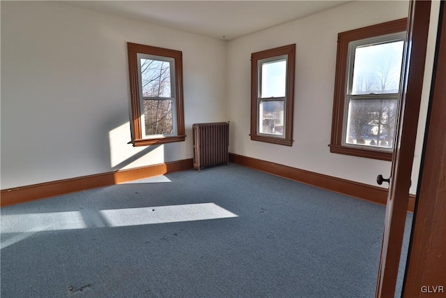 unfurnished room featuring dark colored carpet, a healthy amount of sunlight, and radiator