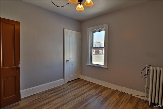 spare room featuring radiator and dark wood-type flooring