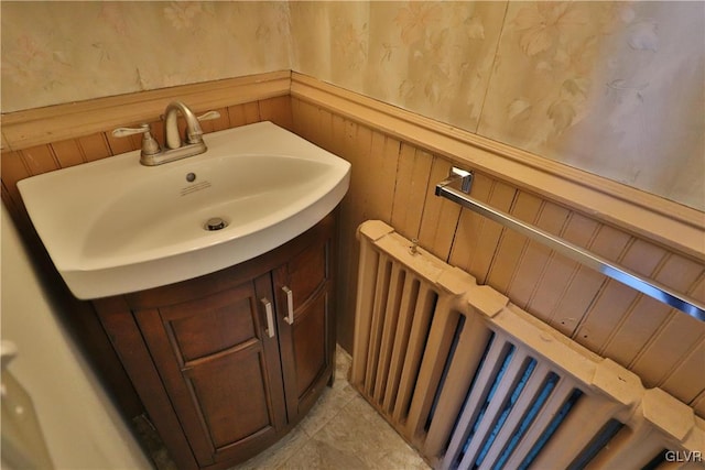 bathroom with vanity, radiator, and wood walls