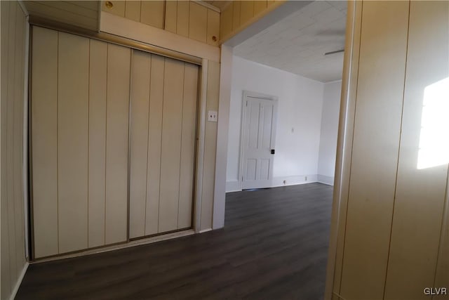 corridor with wood walls and dark wood-type flooring