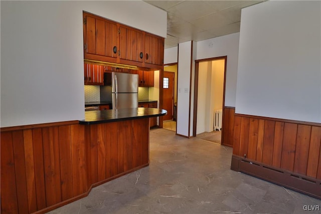 kitchen with kitchen peninsula, stainless steel fridge, radiator heating unit, and baseboard heating