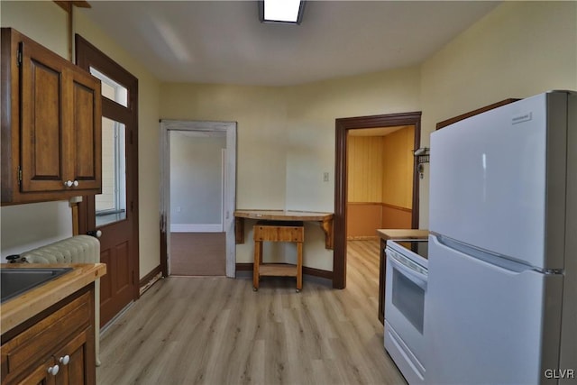 kitchen featuring white appliances, sink, and light hardwood / wood-style flooring