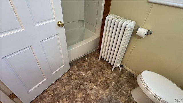 bathroom featuring toilet, radiator heating unit, and a tub