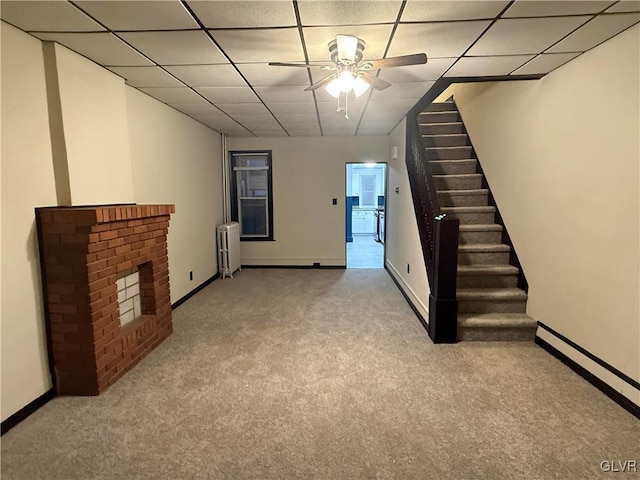 unfurnished living room featuring light carpet, radiator, ceiling fan, a fireplace, and a baseboard radiator