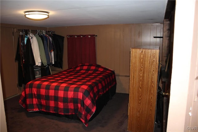 carpeted bedroom featuring wood walls