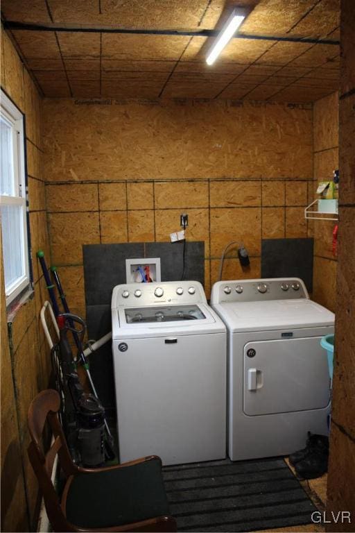 laundry room featuring washing machine and clothes dryer and wooden walls