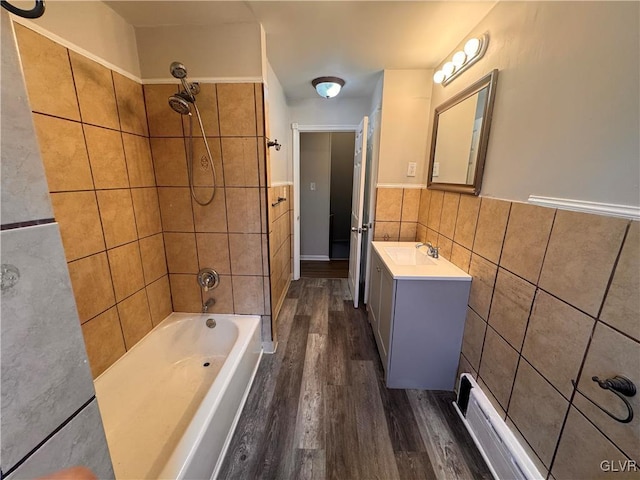 bathroom featuring hardwood / wood-style flooring, vanity, tile walls, and tiled shower / bath