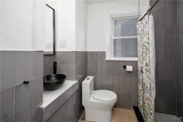 bathroom featuring walk in shower, sink, tile walls, and toilet