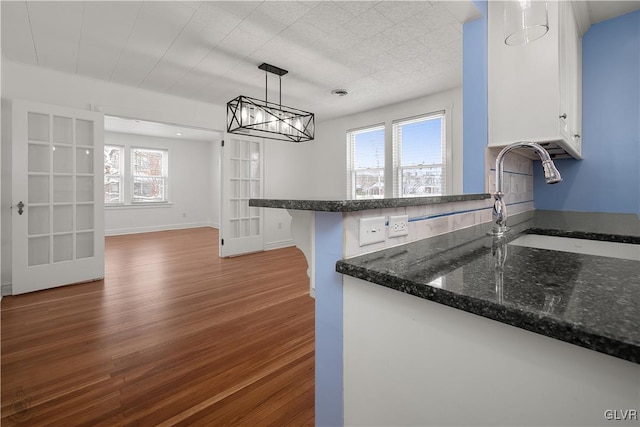 kitchen featuring dark wood-type flooring, white cabinets, sink, hanging light fixtures, and kitchen peninsula