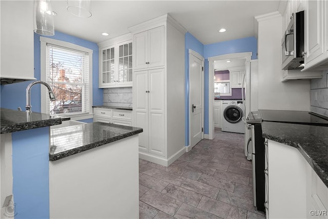 kitchen featuring white cabinetry, electric range, hanging light fixtures, and washer / dryer