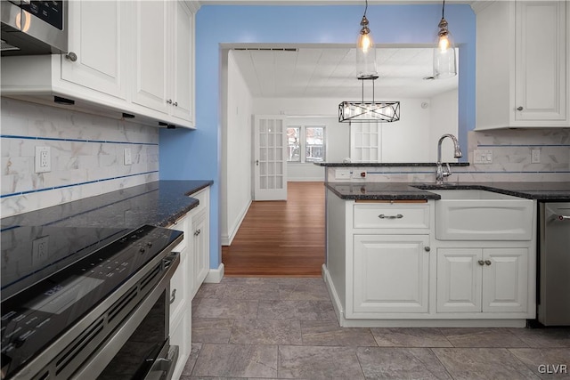 kitchen with electric range, sink, white cabinets, and decorative light fixtures