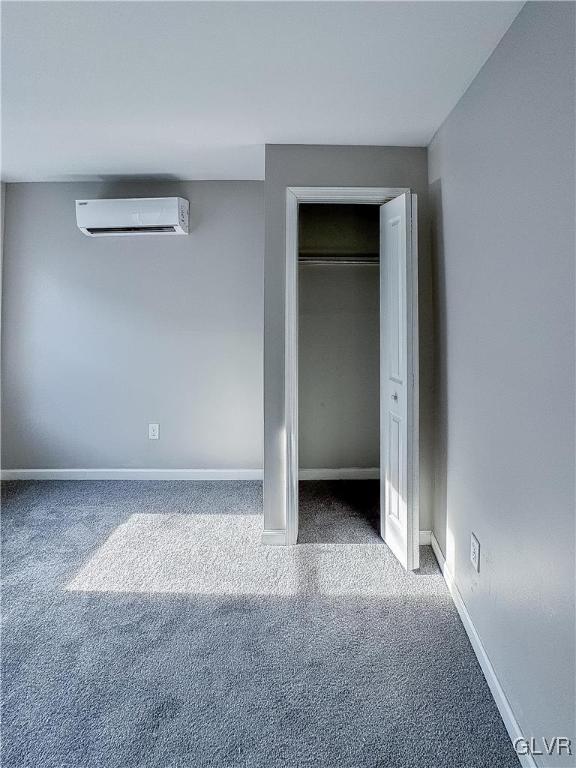 unfurnished bedroom featuring a wall mounted AC, a closet, and carpet