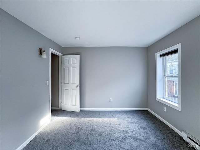 carpeted spare room with a baseboard heating unit