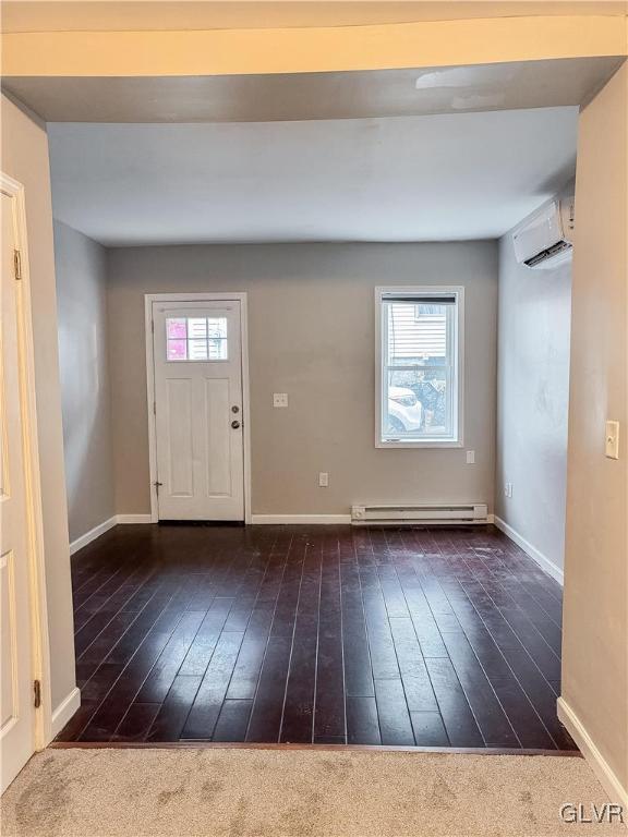 entrance foyer featuring a wall unit AC, a wealth of natural light, dark wood-type flooring, and a baseboard heating unit