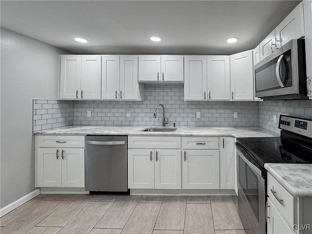 kitchen with white cabinetry, sink, stainless steel appliances, and light stone counters