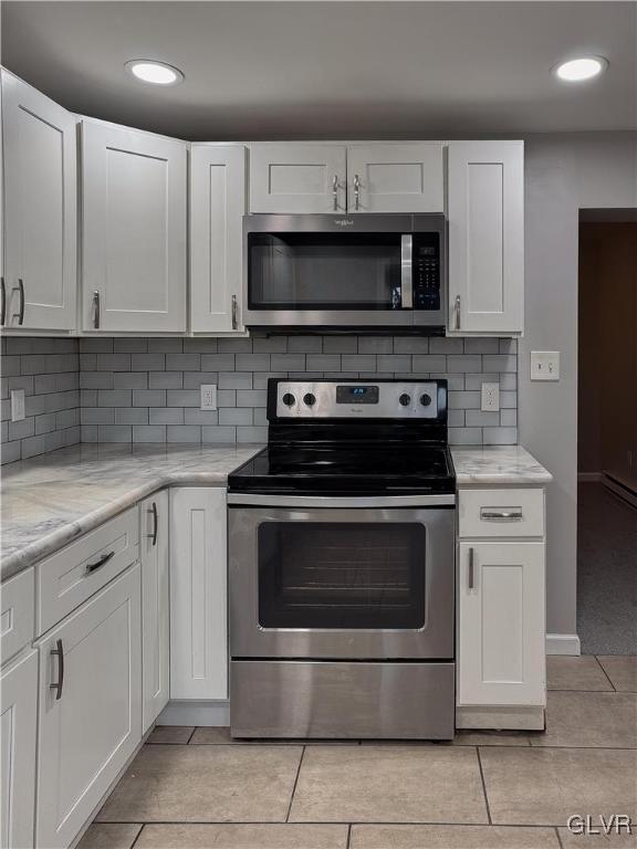 kitchen featuring light stone countertops, light tile patterned floors, stainless steel appliances, and white cabinetry