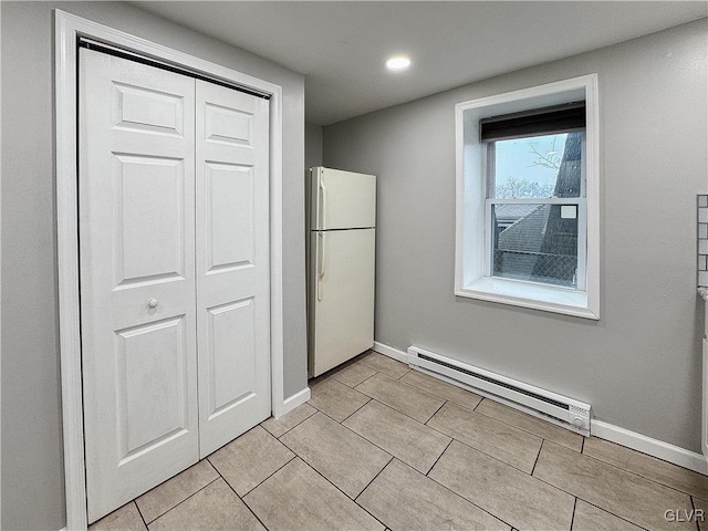 unfurnished bedroom with a closet, white fridge, and a baseboard radiator