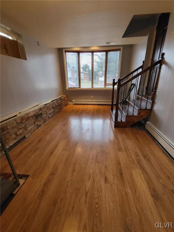 unfurnished living room featuring hardwood / wood-style floors and baseboard heating