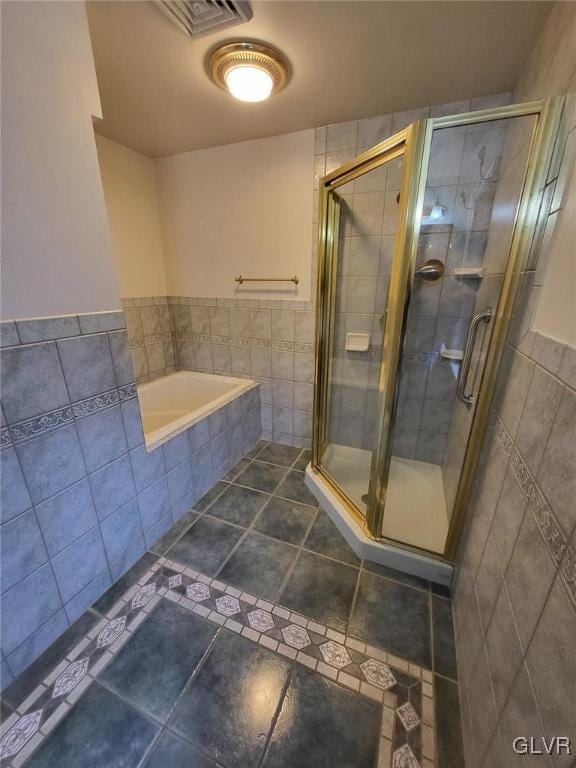 bathroom featuring tile patterned flooring, shower with separate bathtub, and tile walls