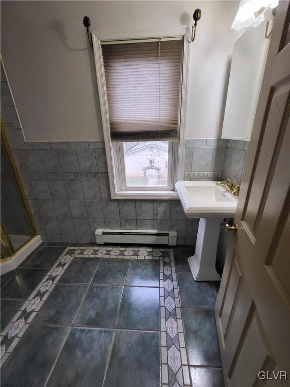 bathroom with tile patterned floors, sink, a baseboard radiator, and tile walls