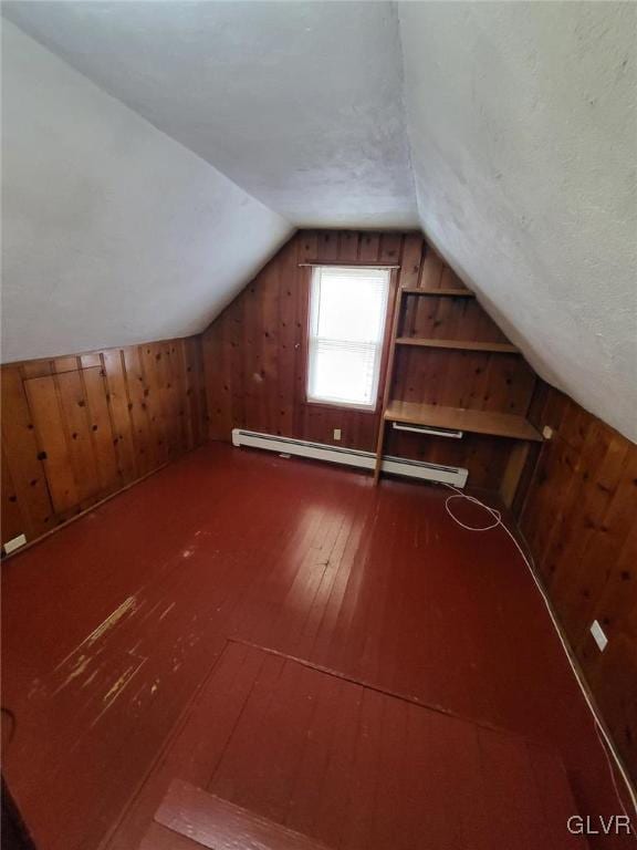 additional living space with lofted ceiling, a baseboard heating unit, wooden walls, hardwood / wood-style flooring, and a textured ceiling