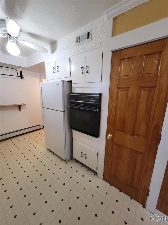 kitchen with a baseboard heating unit, white cabinets, ceiling fan, black oven, and white fridge