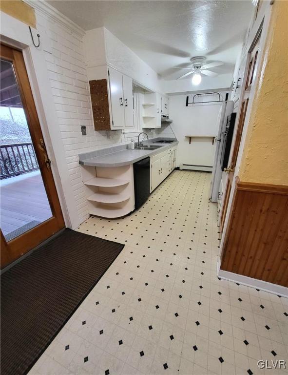 kitchen featuring wood walls, white cabinets, sink, ceiling fan, and black dishwasher