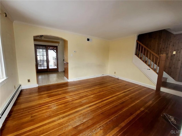 spare room featuring hardwood / wood-style floors, wood walls, ornamental molding, and baseboard heating