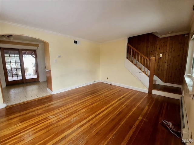 unfurnished living room with french doors, hardwood / wood-style flooring, baseboard heating, and ornamental molding