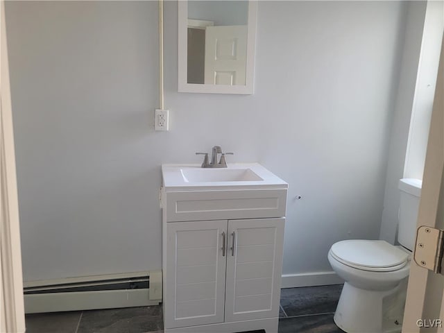 bathroom with toilet, vanity, and a baseboard heating unit