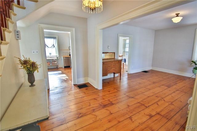 corridor with light hardwood / wood-style floors and an inviting chandelier