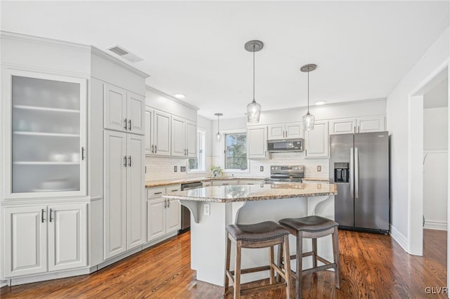 kitchen with white cabinetry, pendant lighting, a kitchen island, and stainless steel appliances