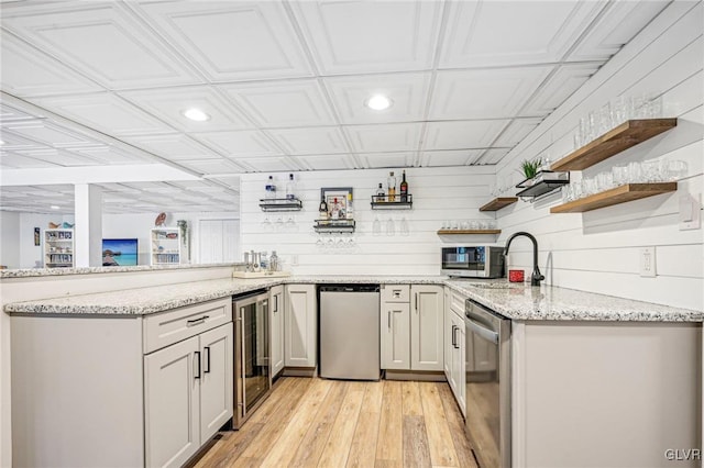 kitchen with light stone countertops, light hardwood / wood-style flooring, wine cooler, and stainless steel dishwasher