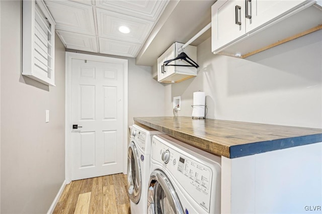 washroom with washer and dryer, light hardwood / wood-style flooring, and cabinets