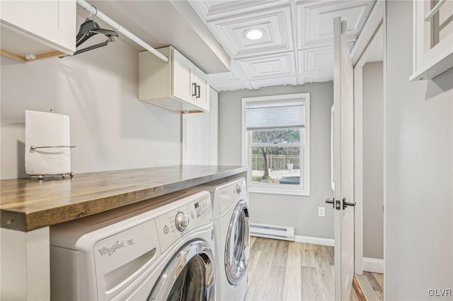 clothes washing area featuring washer and clothes dryer, cabinets, light wood-type flooring, and a baseboard heating unit