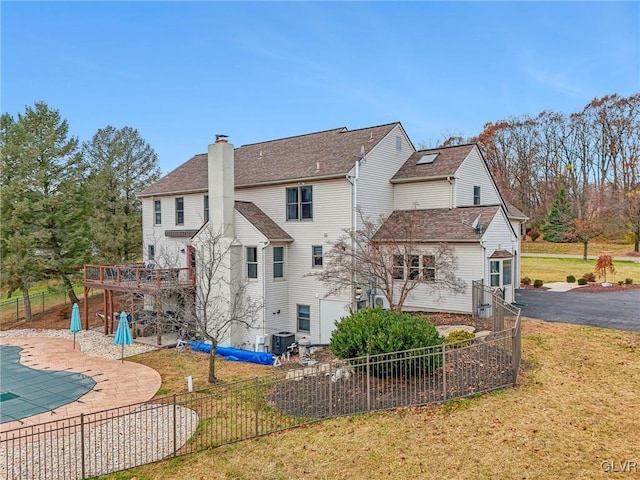 back of house featuring a swimming pool side deck, cooling unit, a patio area, and a lawn