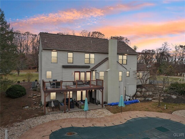 back house at dusk featuring a patio and a pool side deck