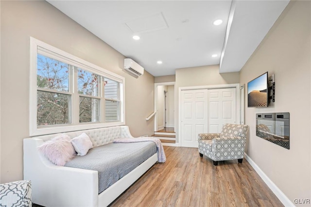 bedroom with a wall mounted AC, a closet, and wood-type flooring