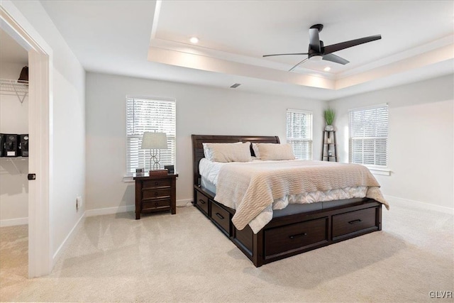 bedroom with a tray ceiling, ceiling fan, and light carpet