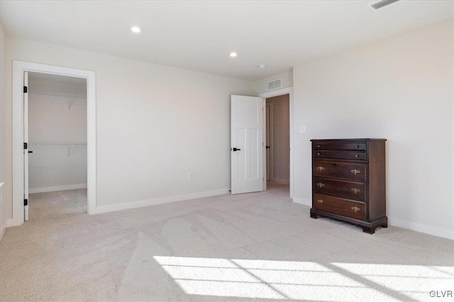 unfurnished bedroom featuring a walk in closet, light carpet, and a closet