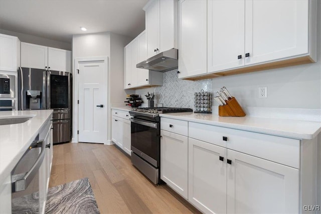 kitchen with white cabinetry, sink, backsplash, appliances with stainless steel finishes, and light wood-type flooring