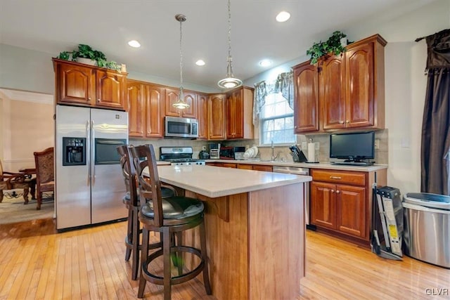 kitchen with decorative backsplash, appliances with stainless steel finishes, light wood-type flooring, pendant lighting, and a kitchen island