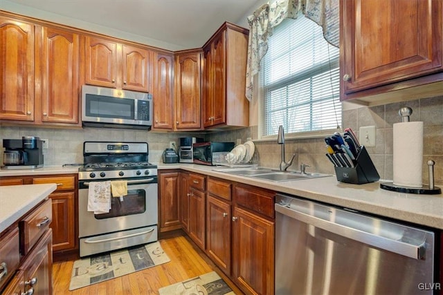 kitchen featuring decorative backsplash, appliances with stainless steel finishes, light hardwood / wood-style flooring, and sink