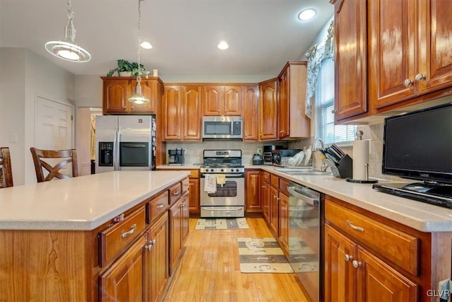 kitchen with decorative backsplash, appliances with stainless steel finishes, decorative light fixtures, and light hardwood / wood-style flooring